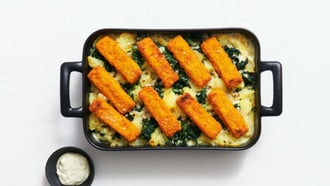 Bastoncini di pesce su patate e spinaci