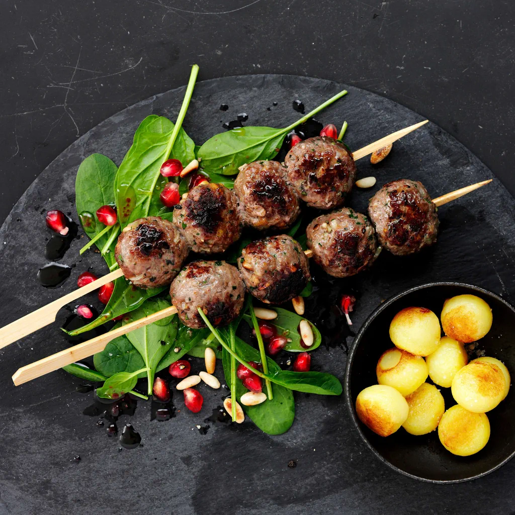 Brochettes de viande hachée d’agneau sur salade d’épinards