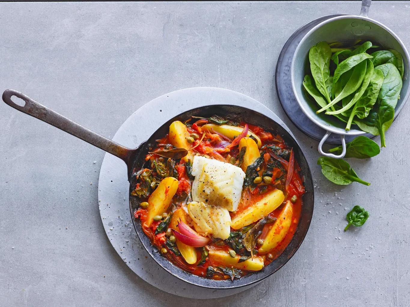 Merluzzo su letto di patate, spinaci e pomodori