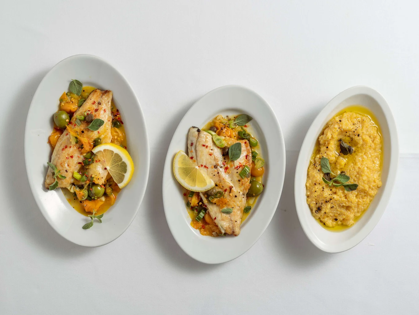 Filetto di pesce su letto di pomodori, capperi e olive