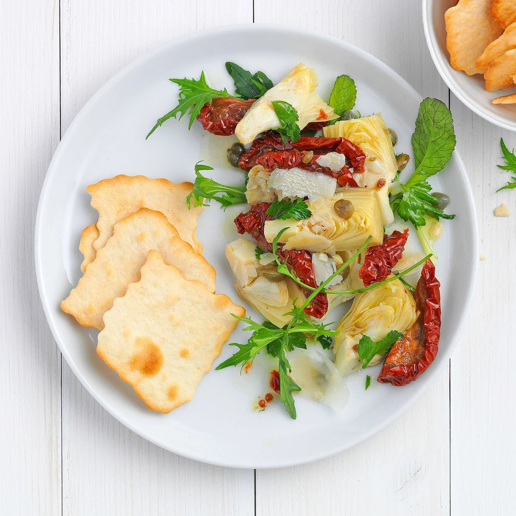Cracker con insalata ai pomodori secchi e carciofi