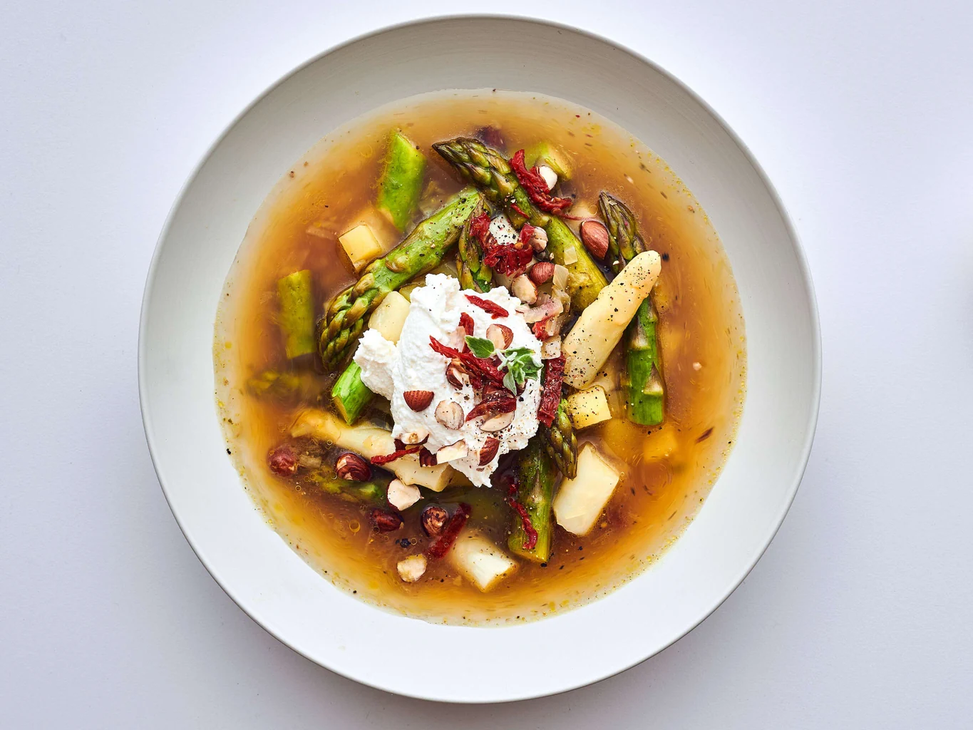 Zuppa di asparagi con topping di ricotta e nocciole